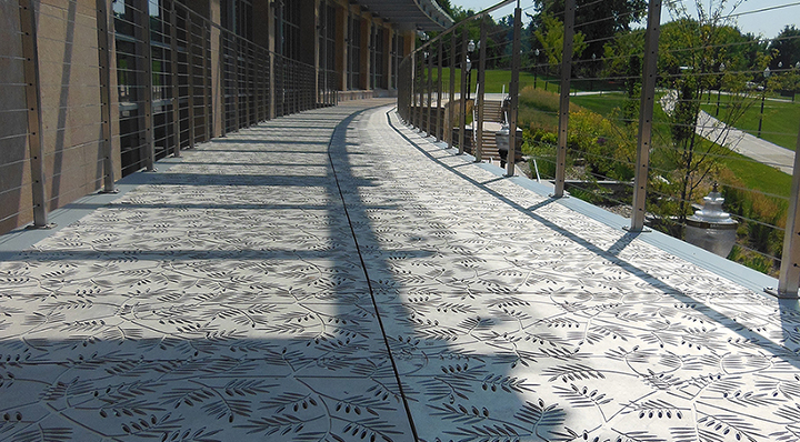 Cast aluminum grate panels in decorative Locust pattern by Iron Age Designs. Arrayed as pedestrian bridge.