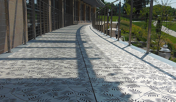 Cast aluminum grate panels in decorative Locust pattern by Iron Age Designs. Arrayed as pedestrian bridge.