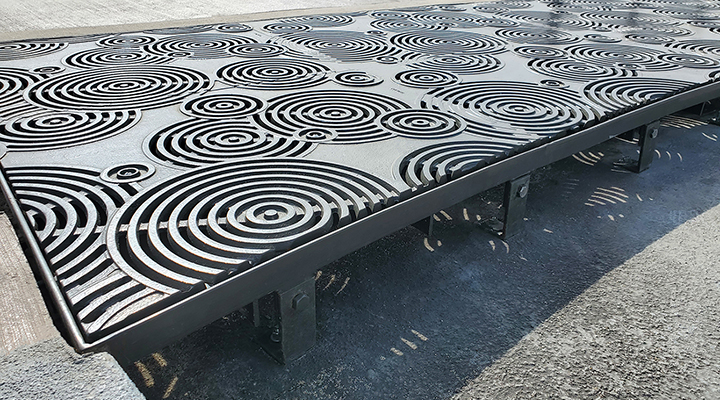 Cast iron grates in decorative Oblio pattern by Iron Age Designs. Arrayed as large stormwater inlet.