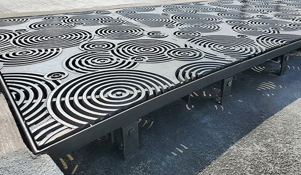 Cast iron grates in decorative Oblio pattern by Iron Age Designs. Arrayed as large stormwater inlet.