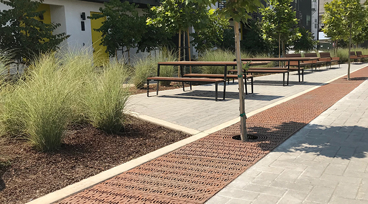 Large, cast iron tree grate in decorative Janis pattern by Iron Age Design. Installed in courtyard next to apartment building.