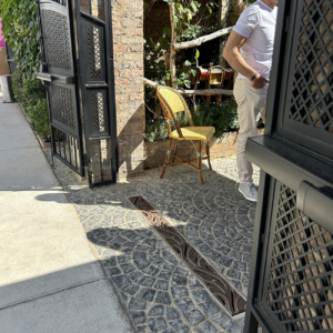 Raw cast iron trench grate in decorative Minnione pattern from Iron Age Designs. Located in outdoor restaurant courtyard.