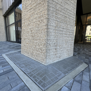 Cast iron trench grate in decorative Rain pattern from Iron Age Designs. Installed in building entryway.