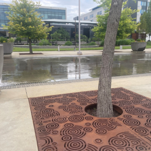 Cast iron tree grate in decorative Oblio pattern from Iron Age Designs. Installed in community plaza.