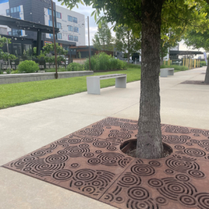 Cast iron tree grate in decorative Oblio pattern from Iron Age Designs. Installed in community plaza.