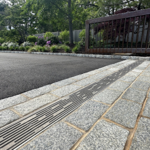 Raw cast aluminum trench grate in decorative Rain pattern from Iron Age Designs. Residential driveway installation.