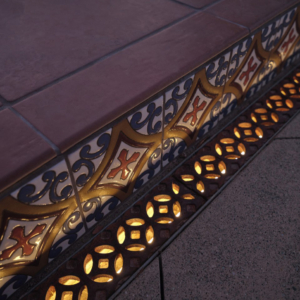 Cast iron trench grate in decorative Interlaken pattern by Iron Age Designs. Lighting installed beneath the grates.