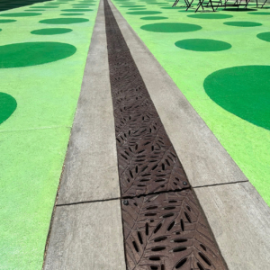 Cast iron trench grates in decorative Locust pattern by Iron Age Designs. Installed in colorful pedestrian plaza.