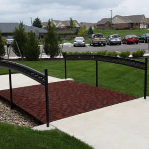 Cast iron grates in decorative Locust pattern by Iron Age Designs. Arrayed as a pedestrian bridge with matching laser cut handrail.